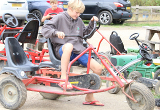 To drenge leger på pedalbiler på Feather Down New Barn Farm, en ferielejr i det østlige England, Storbritannien.
