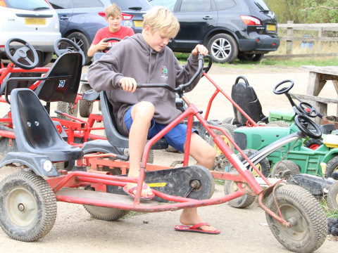 Jungen fahren mit Tretautos auf Feather Down New Barn Farm, einem Ferienpark im Osten Englands, Großbritannien.