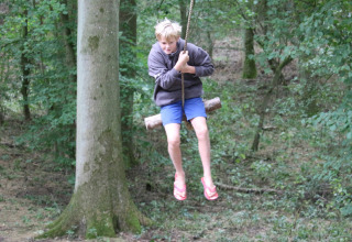 Bambino che dondola su un'altalena a corda alla Feather Down New Barn Farm, parco vacanze nell'Est d'Inghilterra.