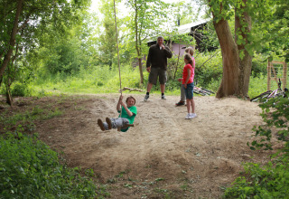 Children play on a rope swing at Feather Down New Barn Farm, a holiday park in East of England, United Kingdom.