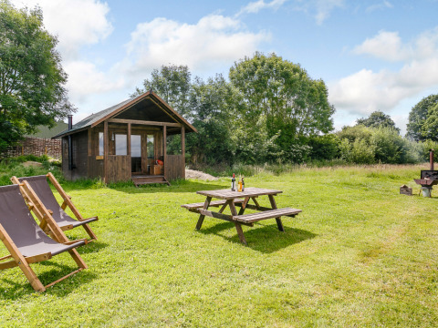 Sfeervol houten huisje met veranda, picknicktafel en ligstoelen op gras bij Feather Down Manor Farm.