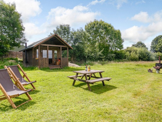 Knusse houten lodge met veranda, picknicktafel en ligstoelen op grasveld bij Feather Down Manor Farm.