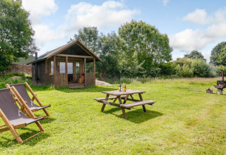 Charmerende træhytte med terrasse, picnicbord og liggestole på en grøn mark ved Feather Down Manor Farm.