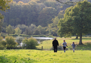 Een gezin wandelt door het grasland van Feather Down Manor Farm met bomen en een meer in het Zuidoosten van Engeland.