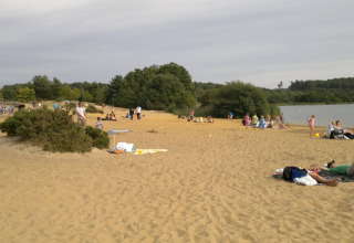 Mensen ontspannen op het zandstrand bij Feather Down Manor Farm vakantiepark, naast een idyllisch meer.