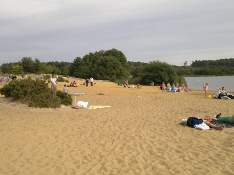 Familien entspannen sich am Sandstrand des Feather Down Manor Farm Holiday Parks neben einem See in England.
