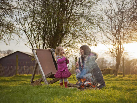 Mama en dochter roosteren marshmallows bij het kampvuur op Feather Down Manor Farm, Zuidoost-Engeland.