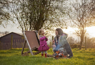 Mother and daughter roasting marshmallows at a campfire at Feather Down Manor Farm, South East England.