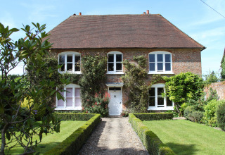 Groot landhuis met bakstenen gevel en verzorgde tuin bij Feather Down Manor Farm, Zuidoost-Engeland.