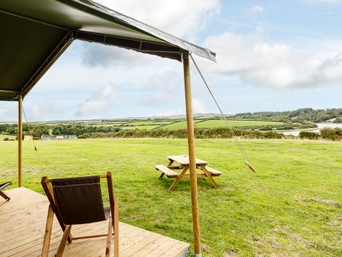 Vista desde la terraza de una tienda en Feather Down Treganhoe Farm en el suroeste de Inglaterra con campo verde.