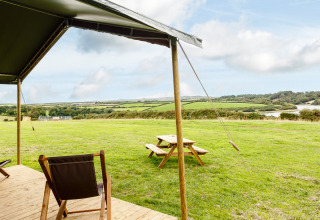 Vista dalla terrazza di una tenda presso Feather Down Treganhoe Farm, Sud Ovest Inghilterra, con prati verdi.