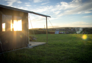 Solnedgang over græsmark ved Feather Down Treganhoe Farm, en feriepark i det sydvestlige England, Storbritannien.
