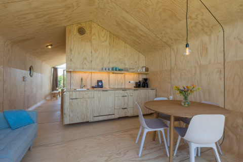 Moderne houten vakantiewoning met open keuken, eettafel en vier stoelen in Welcome In - Zeeland, Nederland.