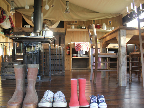 Knus interieur bij Feather Down L'Étable des Mauges en Anjou met vier paar schoenen en houten meubilair.