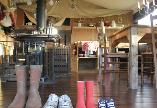 Cozy interior at Feather Down L'Étable des Mauges en Anjou with four pairs of shoes and rustic wooden furniture.