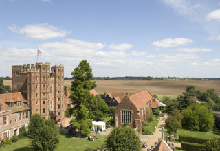 Feather Down Layer Marney Tower feriepark i det østlige England, med historisk bygning og landbrugslandskab.