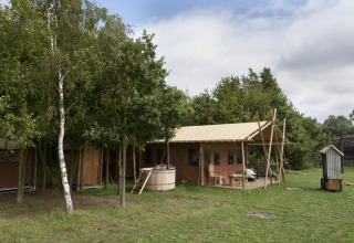 Safari tent at Feather Down Layer Marney Tower holiday park in East of England, surrounded by greenery.