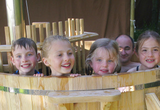 Kinderen en een volwassene genieten van een houten buitenspa bij Feather Down Layer Marney Tower in Engeland.