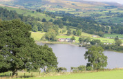 Udsigt over grønne bakker, sø og gårdhuse ved Feather Down Pant y March Farm feriepark i Wales, Storbritannien.
