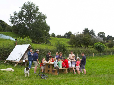 Familias y amigos disfrutan de una comida al aire libre en Feather Down Pant y March Farm, Gales, rodeados de campo.