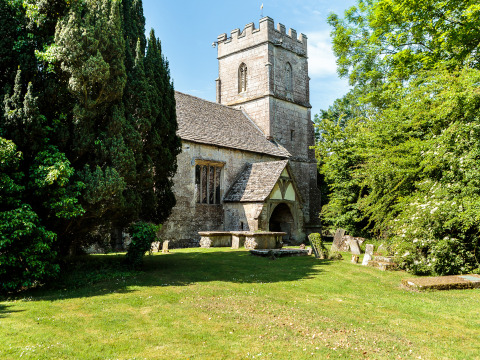 Iglesia de piedra rodeada de árboles y tumbas, en Feather Down Moor Farm, Suroeste de Inglaterra.
