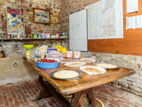 Rustieke ruimte bij Feather Down Moor Farm met snacks, kersen en platbrood op houten tafel, bakstenen muren.