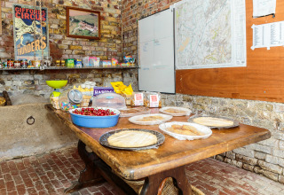 Habitación rústica en Feather Down Moor Farm con snacks, cerezas y panes planos sobre mesa de madera y paredes de ladrillo.