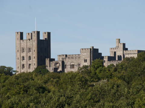 View of a historic castle rising above green trees, taken from Feather Down Hidcote Manor Farm in West Midlands, UK.