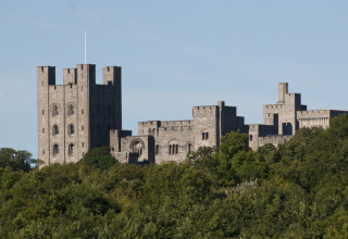 View of a historic castle rising above green trees, taken from Feather Down Hidcote Manor Farm in West Midlands, UK.