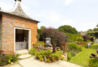 Gezicht op de tuin van Feather Down Hidcote Manor Farm in West Midlands met bloemen en een bakstenen tuinhuis.