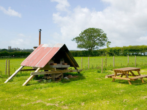 Buitentafereel bij Feather Down Hidcote Manor Farm met picknicktafel, grasveld en schuur, West Midlands.
