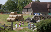 Children walk on a path near hay bales and a barn at Feather Down Lunsford Farm holiday park in England.