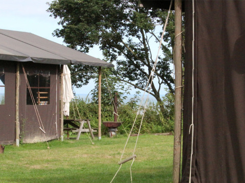 Vista de tiendas y mesa de picnic en Feather Down Lunsford Farm holiday park en el sureste de Inglaterra, Reino Unido.
