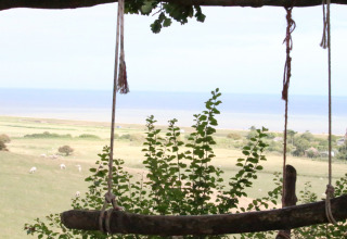Rustic swing overlooking fields, sheep, and the sea at Feather Down Lunsford Farm in Southeast England.