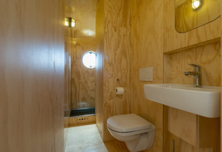 Moderne, minimalistische badkamer met houten wanden, wandtoilet, wastafel en douche in Zeeland, Nederland.