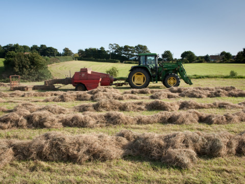 Tractor die hooi baalt bij Feather Down Lunsford Farm, vakantiepark in Zuidoost-Engeland, Verenigd Koninkrijk.