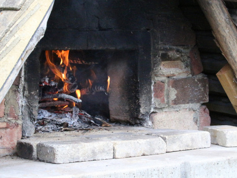 Een houtkachel met vlammen en gloeiende resten, ingebouwd in een bakstenen muur op Feather Down Lunsford Farm.