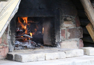 Una stufa a legna con fiamme e braci, incassata in un muro di mattoni presso Feather Down Lunsford Farm.