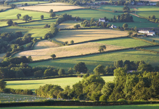 Scenic view of rolling green fields and farmhouses at Feather Down Billingsmoor Farm, South West England.