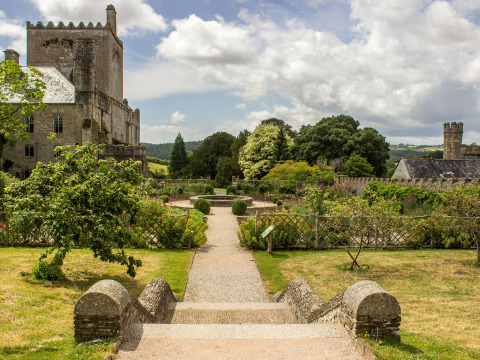 View of a historic stone building and formal garden at Feather Down Billingsmoor Farm in South West England.