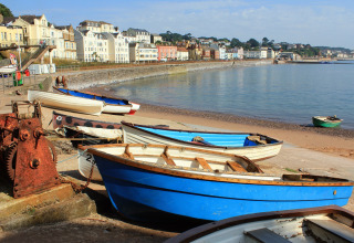 Boats on the shore with colorful houses and a scenic coastline at Feather Down Billingsmoor Farm, England.