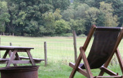 Udendørs scene ved BoerenBed Sunninglye Farm med liggestol, picnicbord og grøn mark i det østlige England.