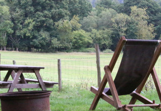 Udendørs scene ved BoerenBed Sunninglye Farm med liggestol, picnicbord og grøn mark i det østlige England.