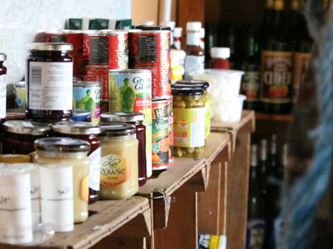 Shelves stocked with canned goods, honey, and jams at BoerenBed Sunninglye Farm holiday park in East England.