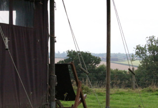 Udsigt fra et telt ved BoerenBed Sunninglye Farm, med grønne marker og træer i det fjerne, East of England.