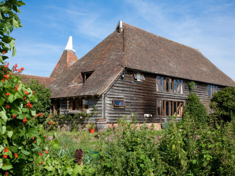 Traditional timber barn at BoerenBed Sunninglye Farm holiday park in the East of England, UK, with gardens.