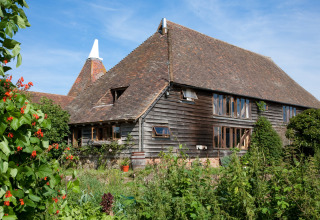 Traditional timber barn at BoerenBed Sunninglye Farm holiday park in the East of England, UK, with gardens.