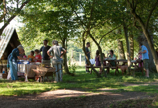Gezinnen genieten van een picknick onder bomen bij BoerenBed Sunninglye Farm vakantiepark in Engeland.