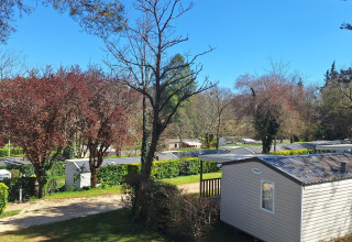 Camping Le Céou en Nouvelle-Aquitaine, Francia, con casas móviles, árboles verdes y cielo azul despejado.