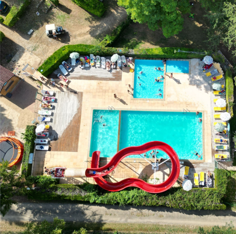 Luchtfoto van zwembad met rode glijbaan en ligstoelen bij Camping Le Céou, Nouvelle-Aquitaine, Frankrijk.